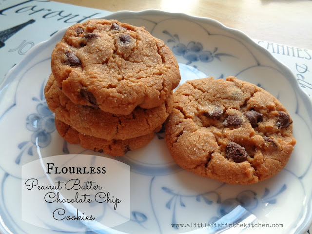 Four tempting peanut butter chocolate chip cookies are stacked on a white ceramic plate with a vintage blue floral pattern. The cookies have perfectly crackled tops and sweet chocolate chips are visible in the tops of each cookies.
