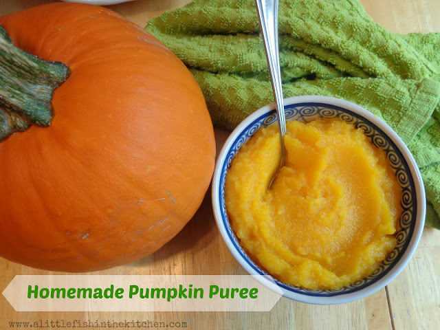 Smooth, freshly prepared pumpkin puree is in a blue and white ceramic bowl which is next to a whole pie pumpkin. A light green tea towel is behind the bowl of pumpkin puree. 