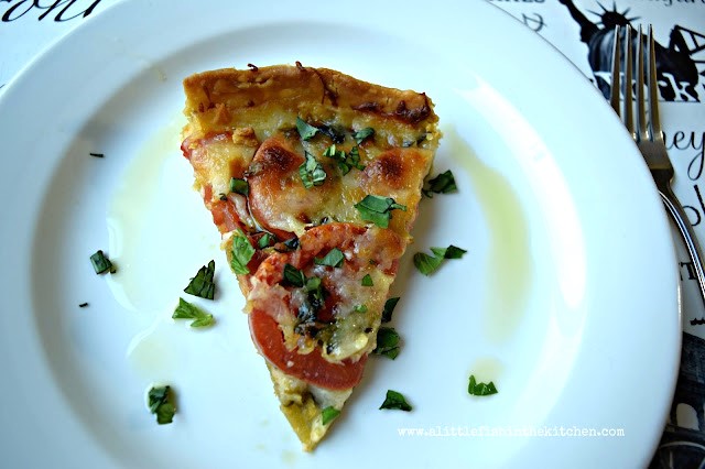 A single slice of cheese tomato tart with pesto is served on a white plate, enjoy!