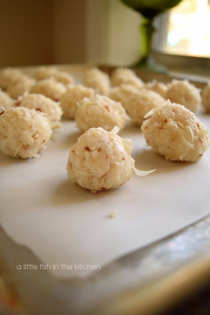 The moistened coconut mixture is rolled into candy balls by hand. The coconut candies are then places on a baking sheet lined with parchment paper to rest until being dipped in melted chocolate.