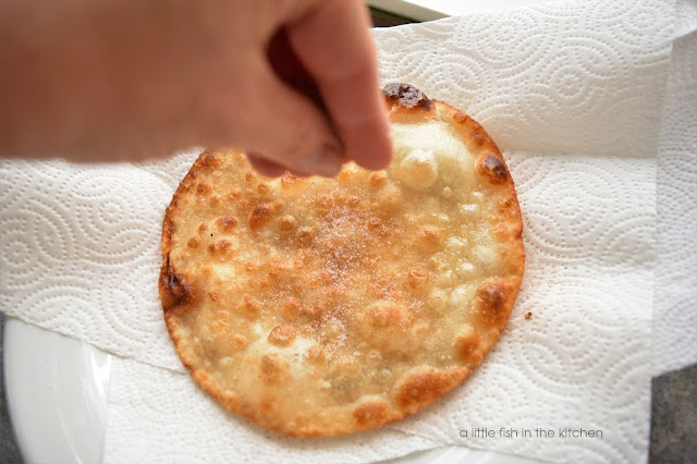 A freshly fried tortilla is generously sprinkled with cinnamon and sugar.