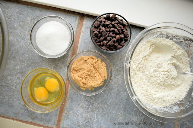 Some ingredients for the skillet cookie separated into bowls: flour, chocolate chips, brown sugar, sugar, eggs,