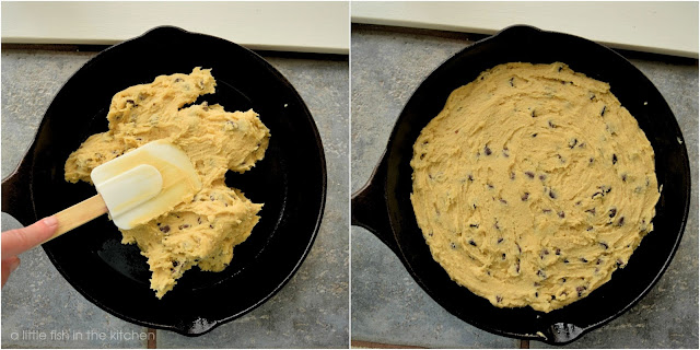 Thick chocolate chip cookie dough is gently pressed into a greased 10-inch cast iron skillet using a silicon spatula.