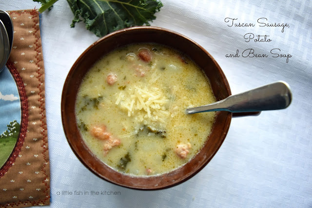 A bowl of creamy copycat Zuppa Toscana is served in a rustic brown ceramic soup bowl. The bowl is on a white linen table cloth. Bits of green kale, Italian sausage, white beans and shredded Parmesan cheese are visible on the surface of the warm soup. 