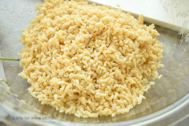 A fluffy freshed cooked portion of brown rice is in a clear mixing bowl. 