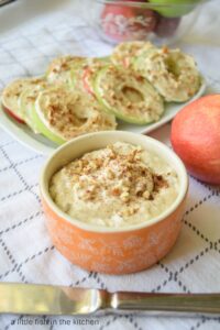 A bowl full of fluffy maple-flavored cream cheese is ready to serve next to a platter of fresh apple cookies. 