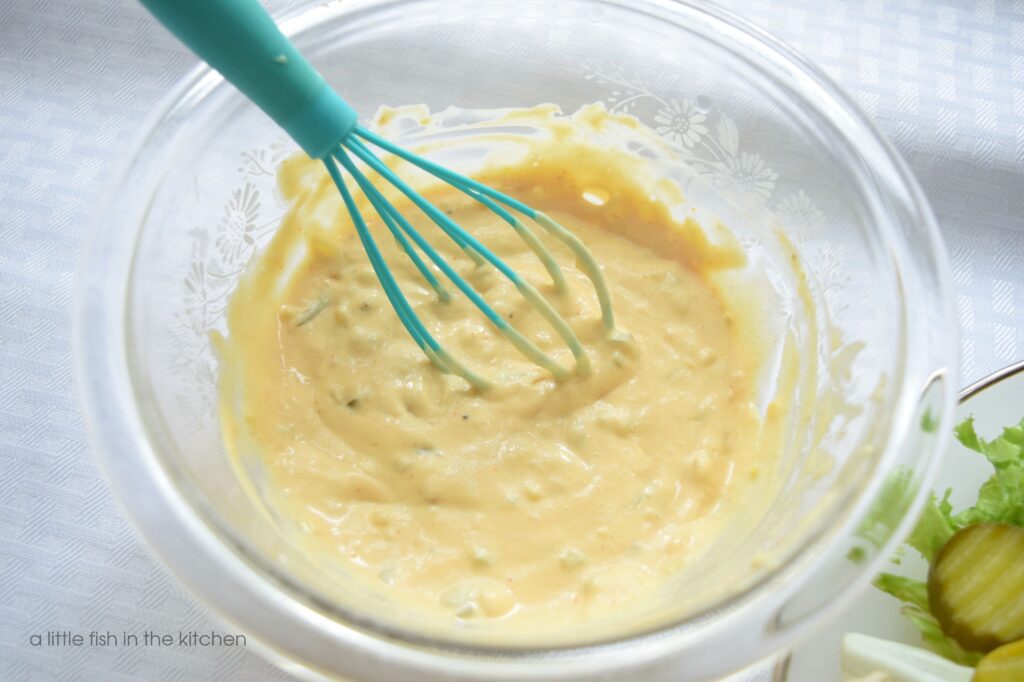Homemade thousand island dressing is better known as secret sauce salad dressing at my house. The cream salad dressing has a slighly pink color and bits of diced pickle are visible in the mix. 