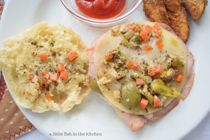 The flavorful olive salad is placed on top of the of the stack of meats and cheeses.  A final layer extraordinary flavor to finish it it off. 