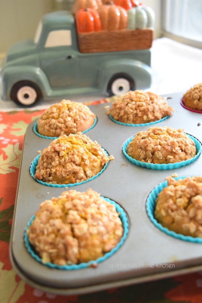 picture of pumpkin oat streusel muffins in a muffin tin with a ceramic teal truck holding pumpkins in it's bed.