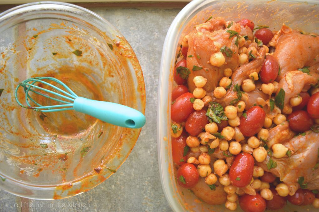 Fresh chicken thighs, chickpeas, whole cherry tomatoes and parsley are coated with the marinade in a large resealable bowl, ready to chill for at least two hours. 