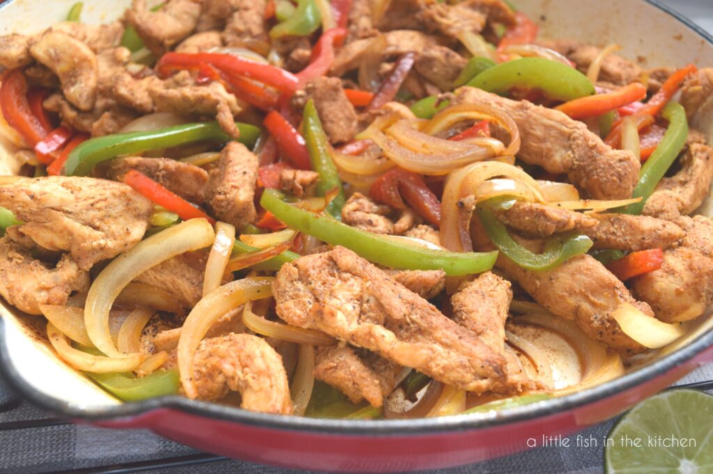 Tender chicken fajitas served with colorful, sauteed red and green bell peppers and sauteed, sliced onions. The spicy Mexican seasonings create a warm, slightly amber color on the tender skillet chicken fajitas.
