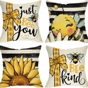 Set of four white pillow covers with bold black, yellow and gold patterns. Large images depict a cute bumblebee and a large sunflower. Two pillows are printed with the phrases "Just Bee You" and the other reads "Bee Kind"