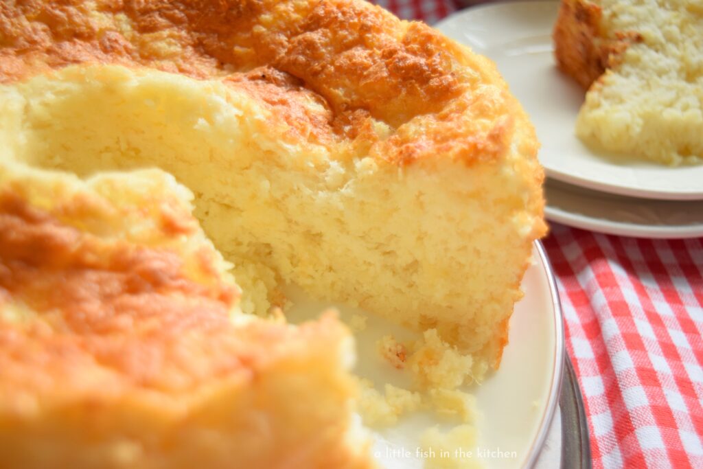 In interior of a freshly sliced pineapple angel food cake reveals a light, golden yellow color with small tidbits of pineapple noticeably distributed throughout the crumb. 