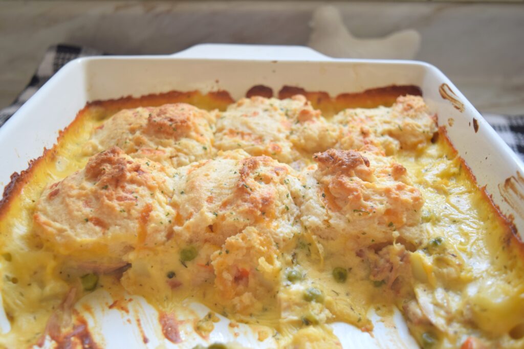 The creamy, golden soup-based filling looks rich and tempting on the inside of the chicken cobbler casserole. Peas, diced carrots, diced potatoes, and shredded chicken are visible through the rustic chicken cobbler. The fluffy Red Lobster biscuits are perfectly golden and inviting.  
