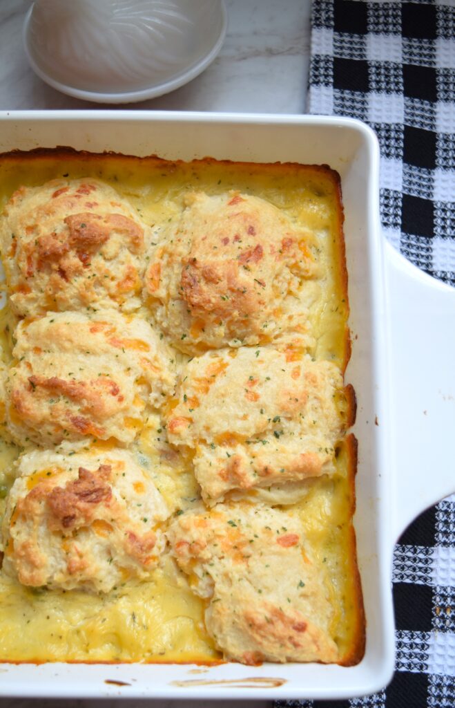 Creamy chicken casserole is topped with golden, buttery Cheddar Bay Biscuits. Bits of potato, carrots and peas are visible in cream-based soup-based filling.